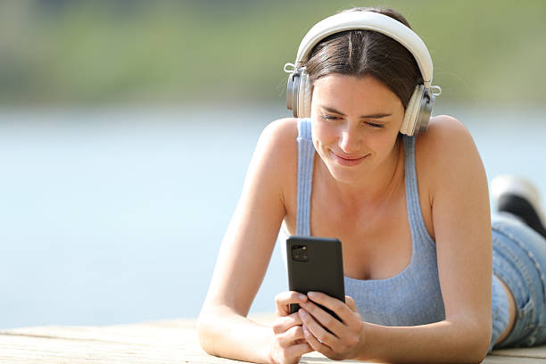 istock Woman wearing headphone using phone in a lake 2206003673