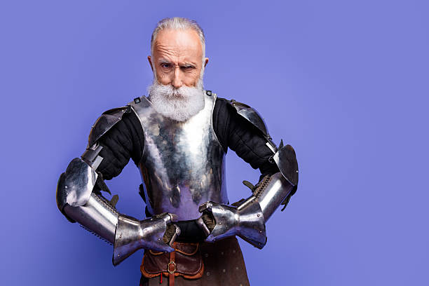 istock Elderly knight in full medieval armor posing against a vibrant purple background, evoking bravery and nobility in a fairytale-like setting 2206003752