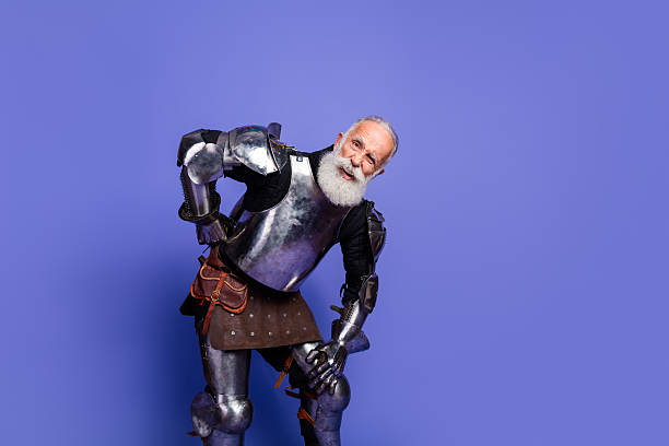 istock Elderly knight with a beard in full armor posing against a violet background 2206003819