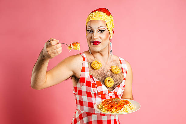 istock Smiling Drag Queen Enjoys Spaghetti With Tomato Sauce Against a Pink Backdrop 2206008246