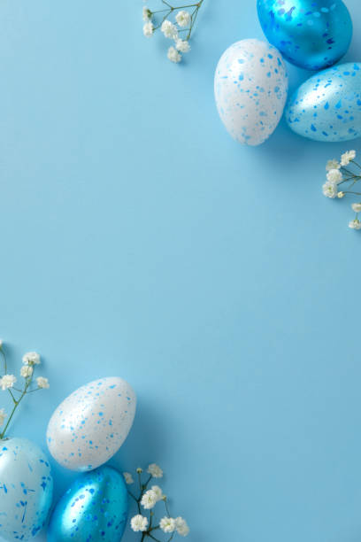 istock Easter vertical background, poster design. Top view speckled blue and white eggs with delicate white flowers on a pastel blue backdrop 2206009282
