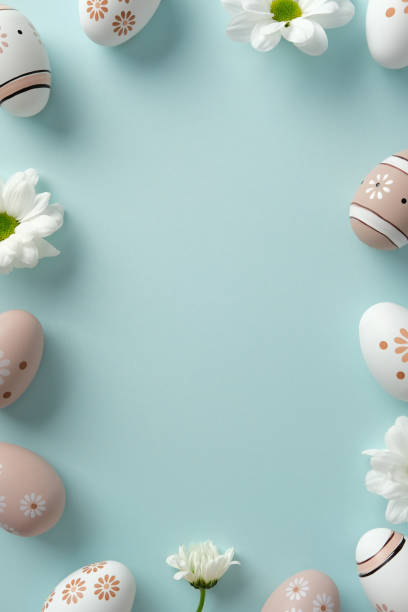 istock Colorful Easter eggs with floral patterns and white daisies on pastel blue background. Easter frame, vertical banner design 2206009698
