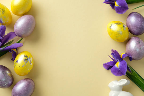 istock Easter flat lay composition with Easter eggs in purple and yellow shades with metallic details, and blooming purple irises on pastel yellow background. 2206010355