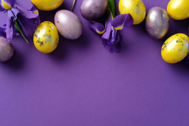 istock Happy Easter banner design. Flat lay composition with vibrant yellow and purple eggs, golden accents, and fresh purple irises on a purple background 2206010578