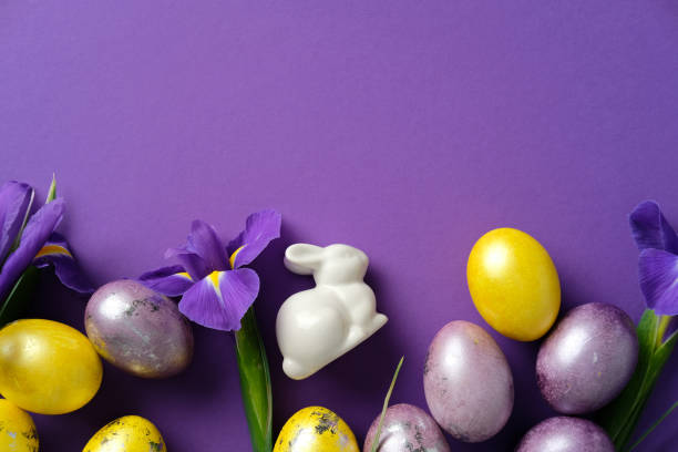 istock Happy Easter concept. Flat lay ceramic bunny, colorful eggs, and vibrant purple irises on a purple background 2206010620