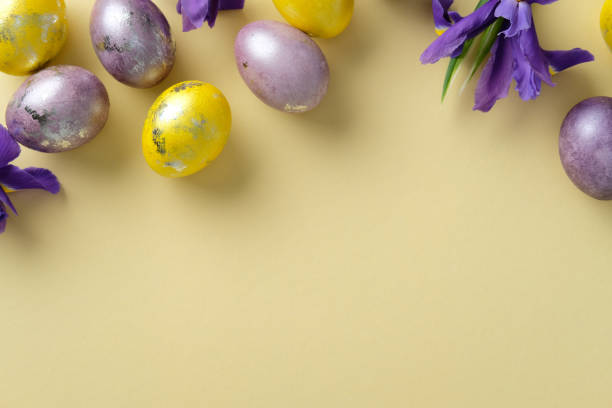istock Happy Easter greeting card design. Top view Easter scene with yellow and purple eggs featuring metallic accents, paired with blooming irises on a pastel yellow background 2206010730