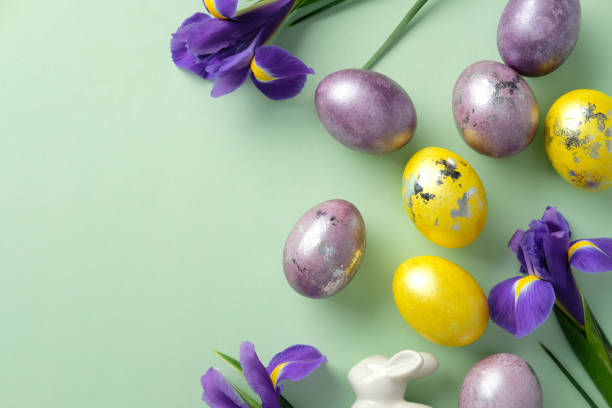istock Vibrant Easter eggs and purple irises arranged on a pastel green background. Flat lay, top view 2206010853