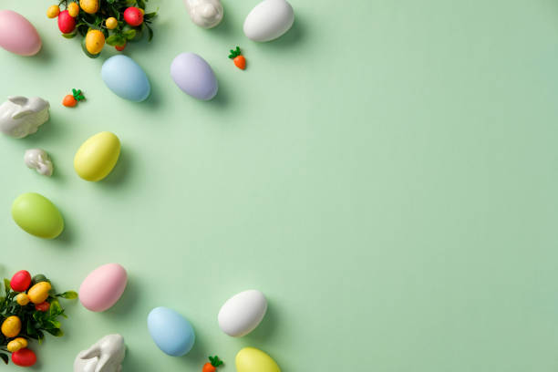 istock Happy Easter flat lay composition. Top view bowl of pastel colored Easter eggs, ceramic bunnies, decorative carrots on green background 2206011843