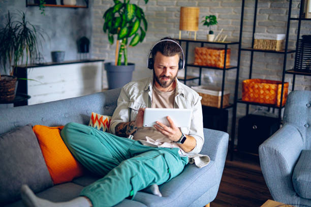 istock Man with headphones using tablet while relaxing in the couch at home 2206013296