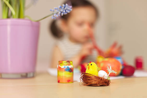 yellow chick in nest and blurred background with child drawing on easter