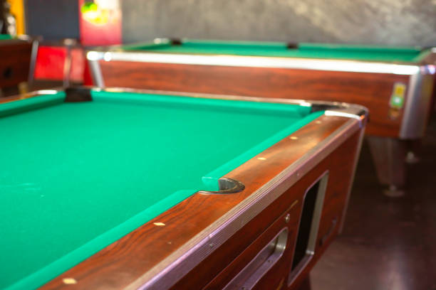 Side pocket of pool table in chrome cast, metal mirror finish drops, strong and hard wearing, classic indoor game room in Houston, Texas, green playfield cloth covered, ball pocketing rolls. USA bolsillo lateral de la mesa de billar en fundición cromada, gotas con acabado de espejo de metal, fuerte y resistente, sala de juegos interior clásica en houston, texas, tela verde del campo de juego cubierta, rollos de bolsillo para bolas