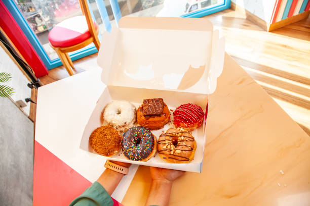 istock Hand holding doughnut box of assorted mixed hand made brioche donuts. 2206023011