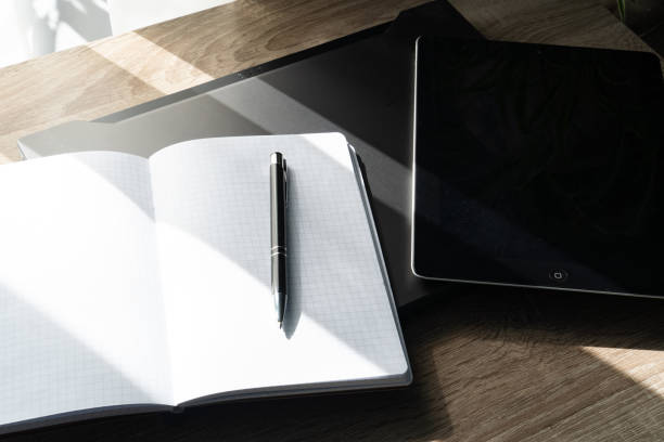 A workspace featuring a laptop with Cyrillic keyboard, a notebook with graph paper, and a pen on a wooden desk—perfect for productivity and planning themes.