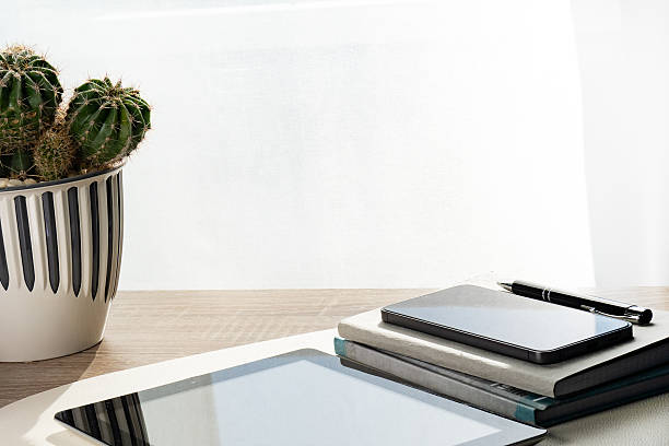 Minimalist Workspace with a Potted Cactus, Notebook, Tablet and Smartphone.