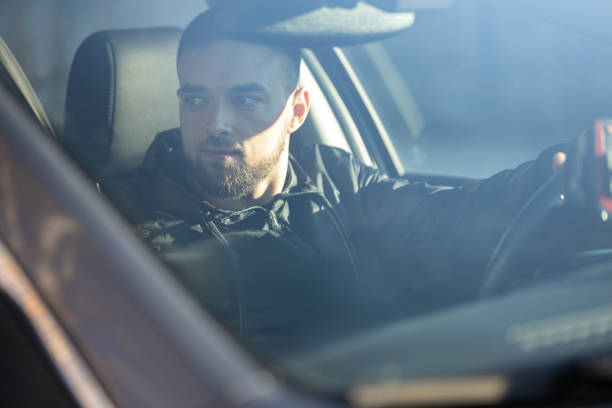 istock A smiled handsome man sits behind the wheel, driving a car 2206029713
