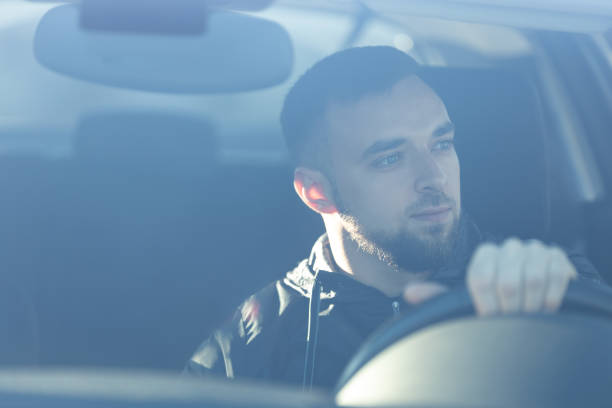 istock A smiled handsome man sits behind the wheel, driving a car 2206029747