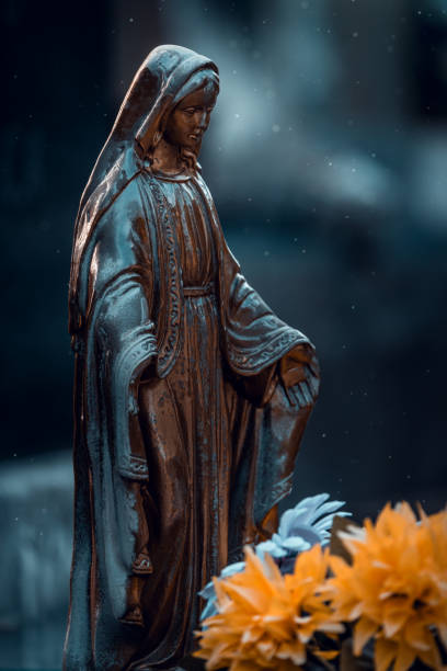 istock Bronze Virgin Mary statue with flowers  in cemetery 2206030194