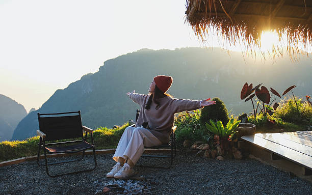 istock A woman with open arms sitting with cat and looking at a beautiful mountain view and sunrise 2206030607