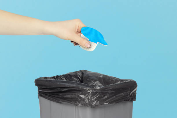 istock throw portion packs with cream in the trash can, portion packs with cream in hand in front of trash can 2206033260