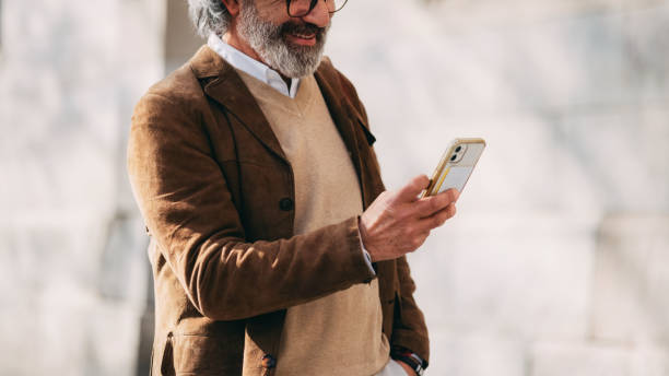 istock Smartly Dressed Senior Man Using Smartphone Outdoors in Casual Environment 2206033784
