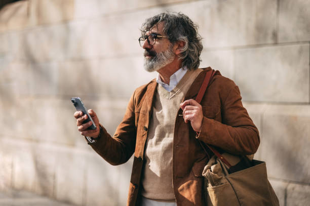 istock Man Outdoors Using Smartphone While Carrying Shoulder Bag in Casual Attire 2206033790