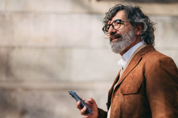 istock Stylish Mature Man Holding Smartphone Outdoors in Bright City Setting 2206033813