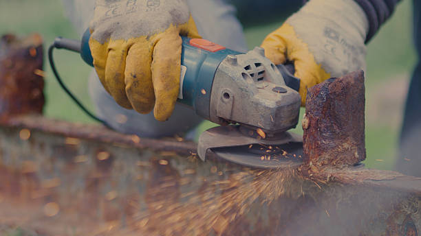 Angle grinder causing sparks while being used to cut metal, Mechanic using electric grinder to cut steel with firelight flicker, Sparks flying from the disc of the angle grinder cutting steel