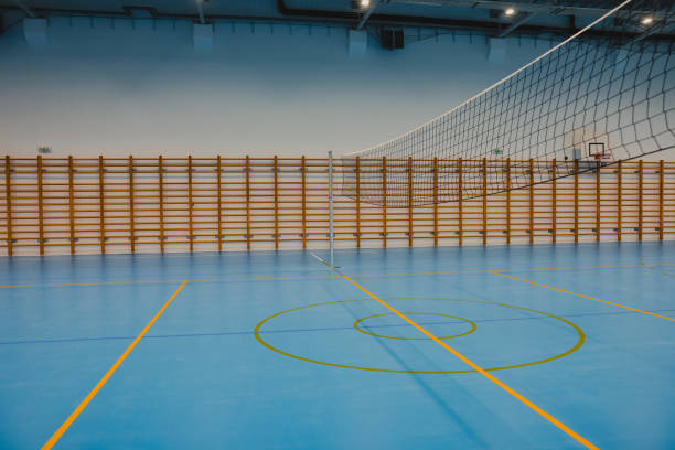 istock Volleyball net stands on blue epoxy floor in empty gym 2206035494