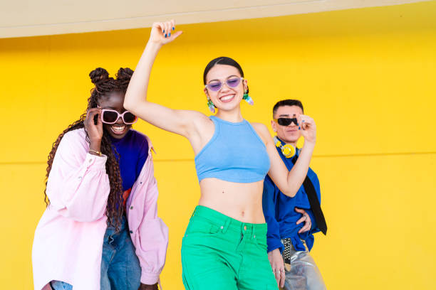 istock Young adults dancing energetically, sharing joy near bright yellow wall, showcasing vibrant urban lifestyle and friendship 2206037437