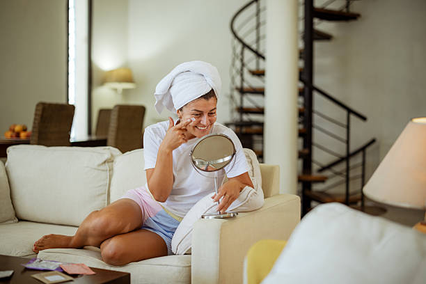 istock Smiling young woman applying face cream while doing skin care routine at home 2206037859