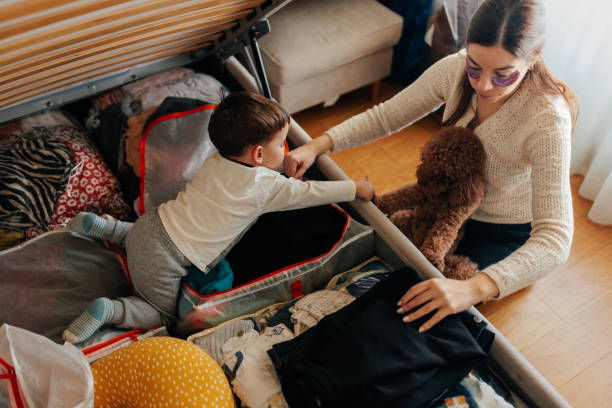istock Mother and son arranging clothes in storage bed at home 2206039887