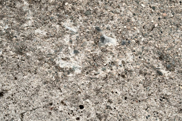 Dirty concrete wall with gravel stones texture background.