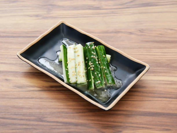 istock Spicy Marinated Cucumber Sticks sprinkled with sesame seeds served in black dish isolated on table side view of Japanese cousin 2206042795
