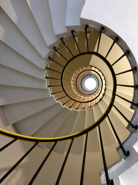 istock View looking up a spiraling staircase, highlighting its circular and symmetrical design. The railing curves inward, drawing attention to the architectural patterns and depth. 2206042984