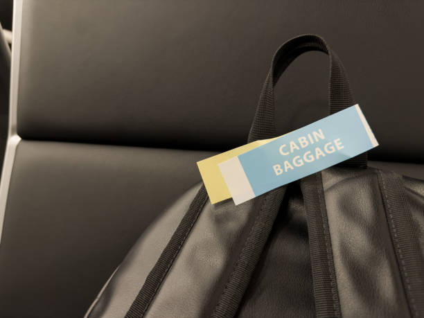 Airplane travel with backpack for carry on luggage, easy travel without large bag as luggage. Sticker on handle of black backpack showing hand luggage on an airplane