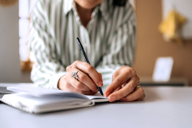 istock Close up shot of senior woman taking notes while working from home 2206045449