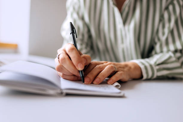 istock Close up shot of senior woman taking notes while working from home 2206045459