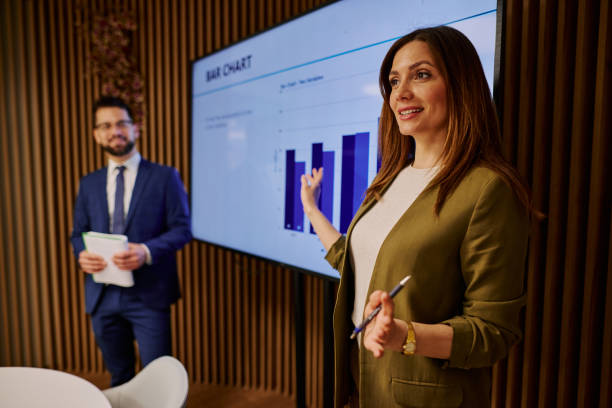 istock Businesswoman presenting bar chart on large screen during a meeting 2206047152