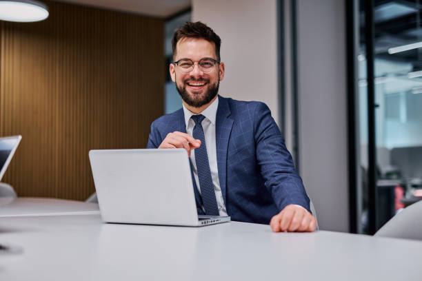 istock Smiling businessman working with laptop in modern office 2206047423