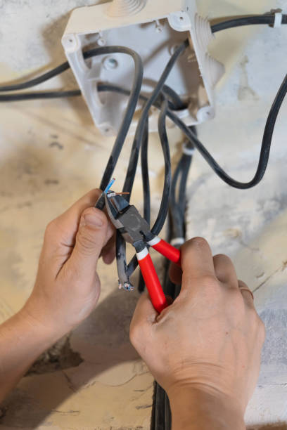 istock Electrician using pliers to skillfully cut and strip electrical wires, engaging in vital maintenance and installation work to ensure safe and efficient connections within the electrical system 2206047959