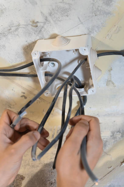istock Electrician is working on a ceiling, carefully installing and connecting electrical wires within a junction box during a home renovation or construction project. Vertical photo 2206047967