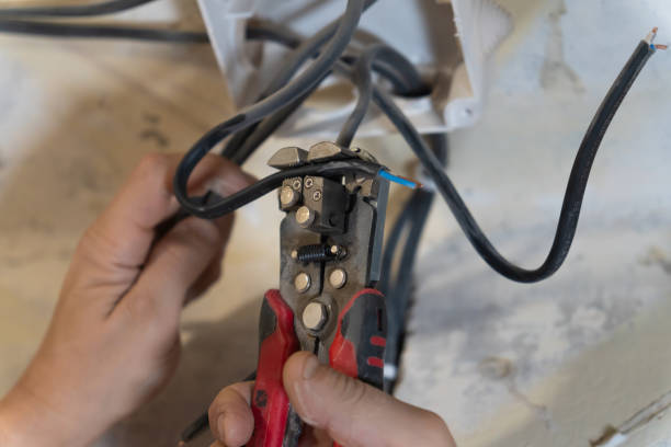 istock Close-up of electrician's hands using wire strippers to carefully remove insulation from electrical wires, preparing them for connection in electrical work 2206047984