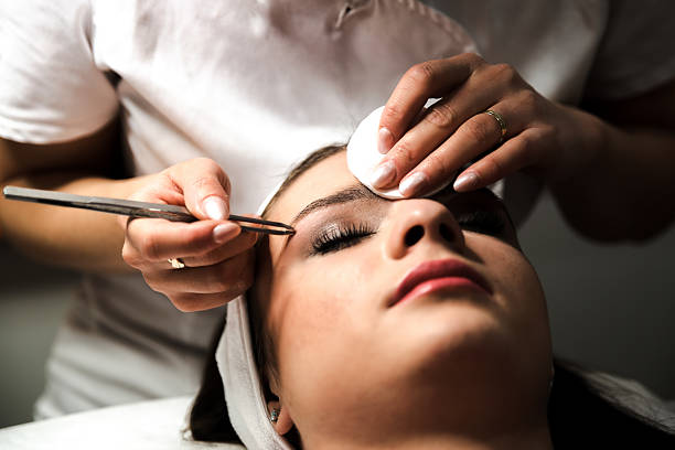 Beautician making eyelash extension procedure in beauty salon. Permanent eylashes make up.