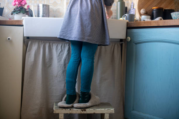 Little girl's legs on a stool by the kitchen sink