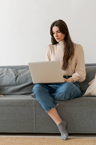 istock Woman is sitting on a couch and using a laptop 2206054304
