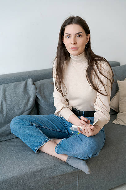 istock Woman is sitting on a couch with a book in her hand 2206054400