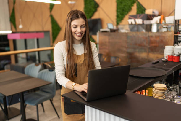 istock Happy female employee using a laptop while working in a coffee shop 2206058971