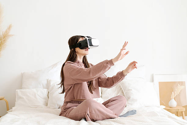 istock Woman is sitting on a bed wearing a virtual reality headset 2206062458