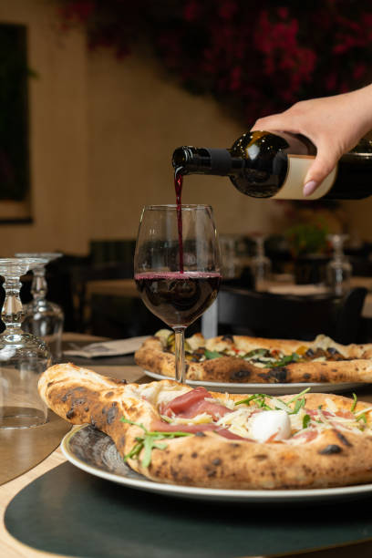 istock Red wine poured on a restaurant table with pizza 2206070410