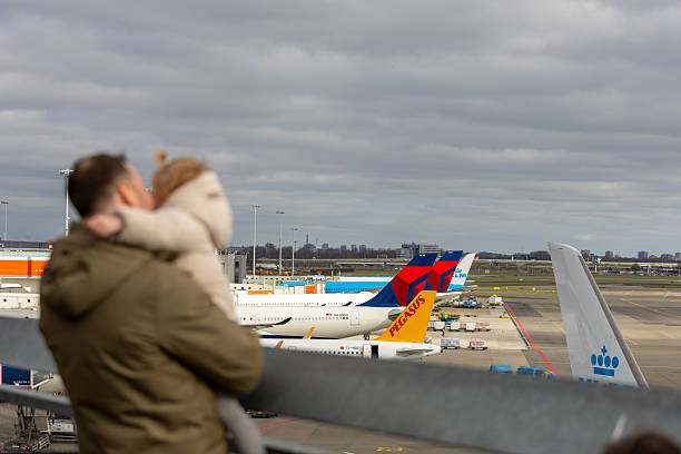 Amsterdam, Netherlands—Mar 14, 2025: a father holding his kid watching planes at schiphol airport